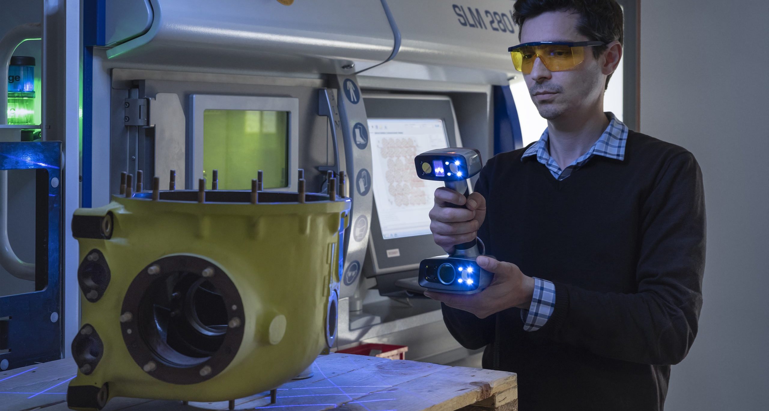 Ingénieur INOVSYS scannant une pièce aéronautique devant une imprimante 3D métallique